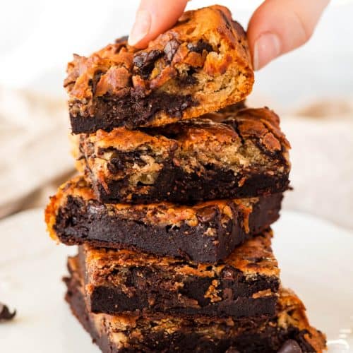 Five healthy blondie brownies stacked on top of each other - someone is holding the top one.