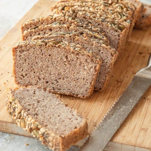 A sliced loaf of Fermented Buckwheat Bread on a chopping board, there's a bread knife on the right.