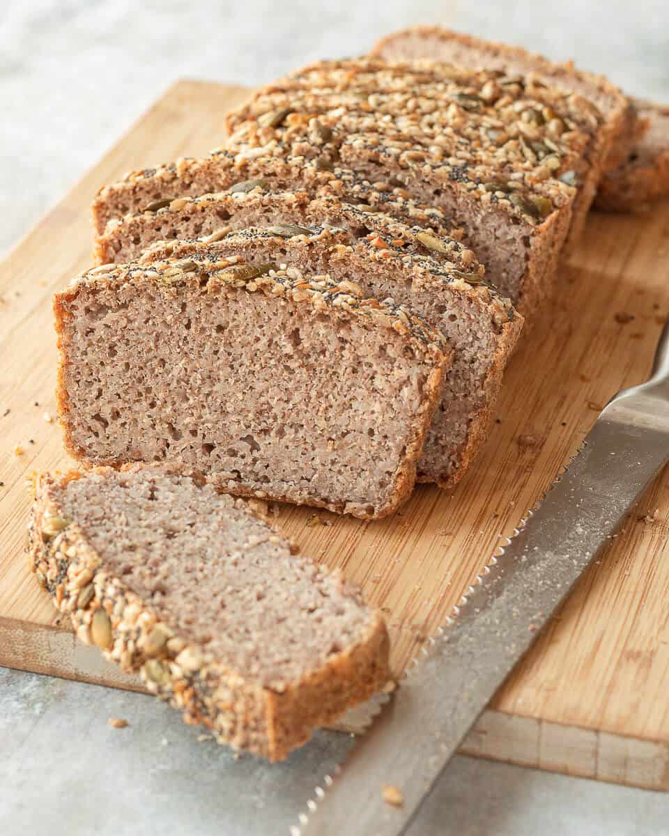 A sliced loaf of Fermented Buckwheat Bread on a chopping board, there's a bread knife on the right.