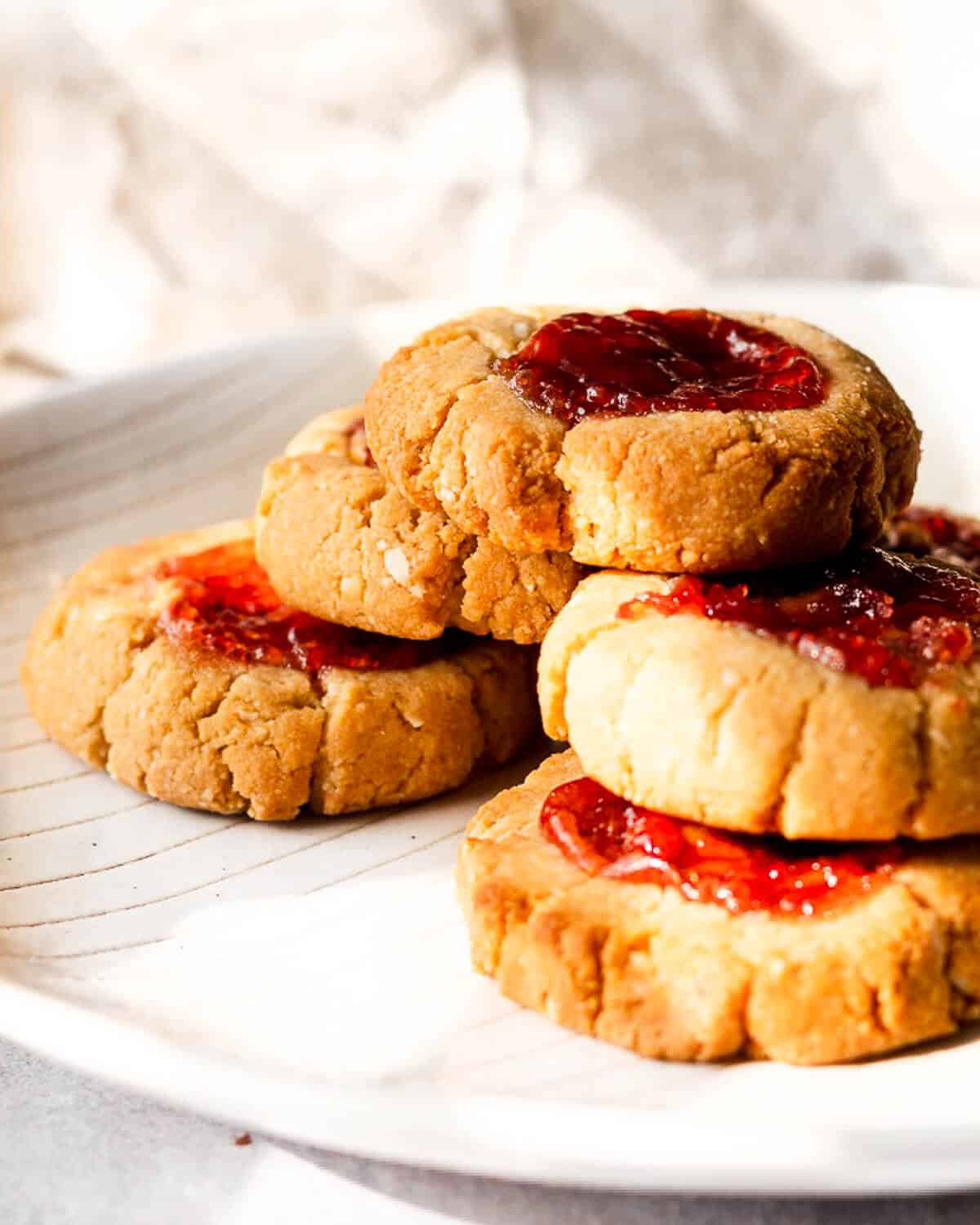 Five Pb & J Cookies stacked on top of each other in a pyramid form on a white plate.