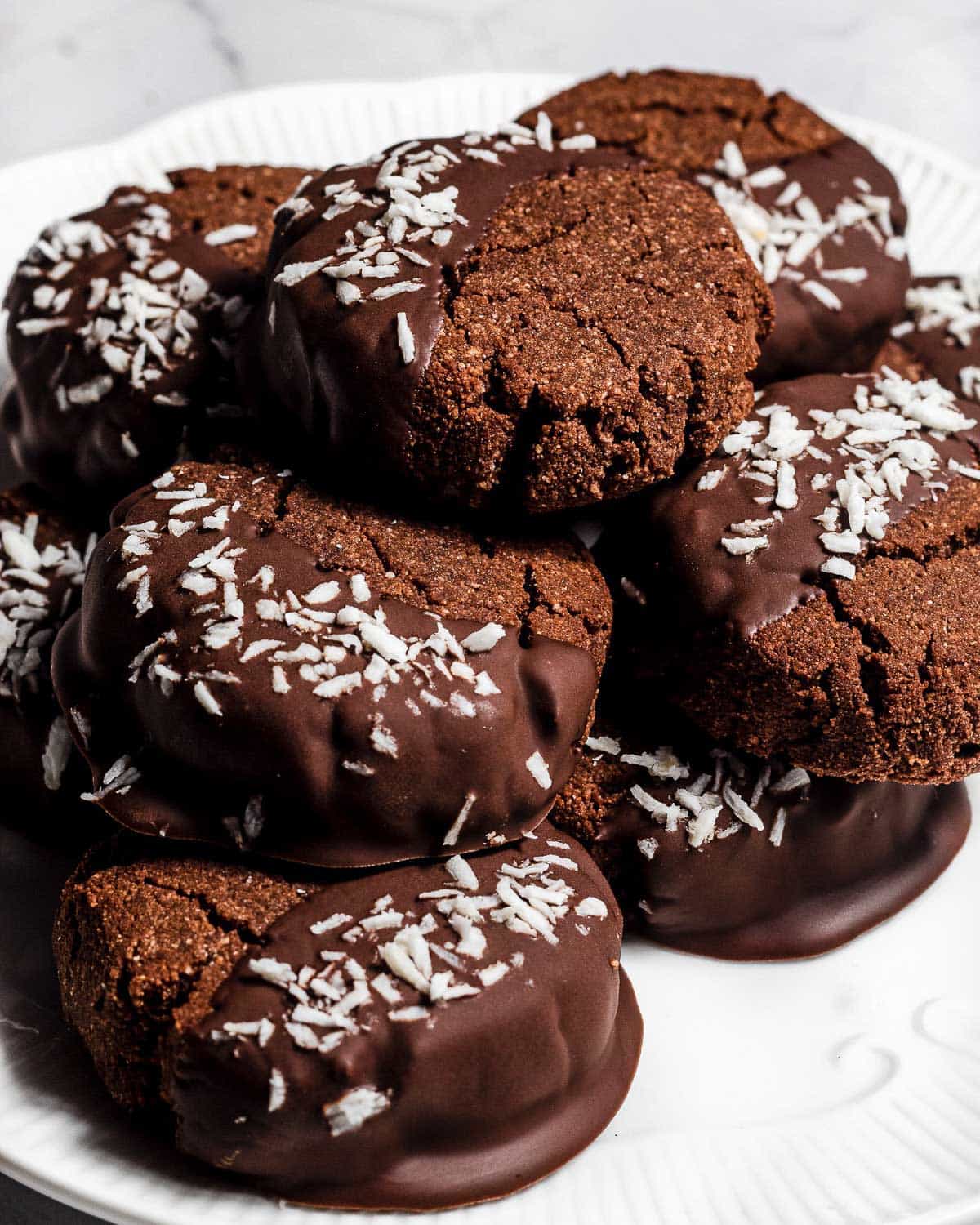 A pile of chocolate coconut biscuits on a white plate.