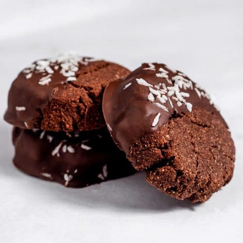 Two chocolate coconut biscuits on top of each other and a third biscuit is angled up against them.