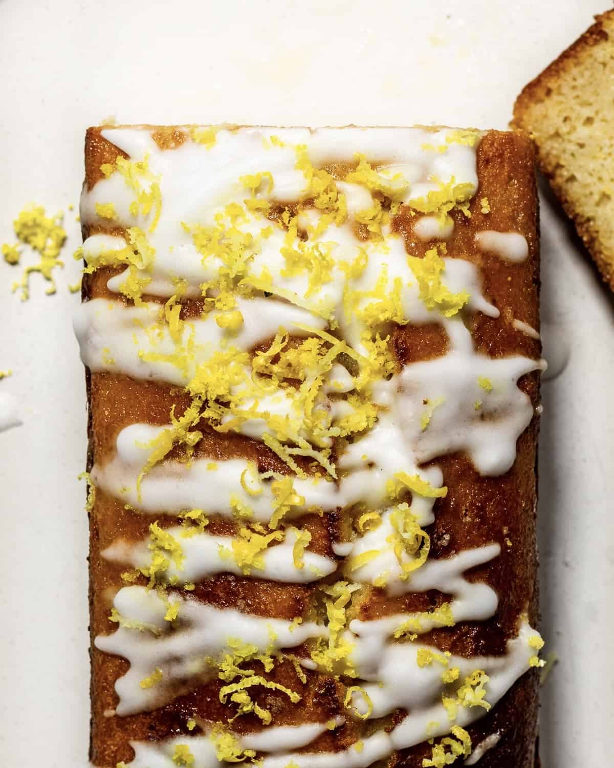 A lemon drizzle loaf cake with lemon icing and lemon zest photographed from above.