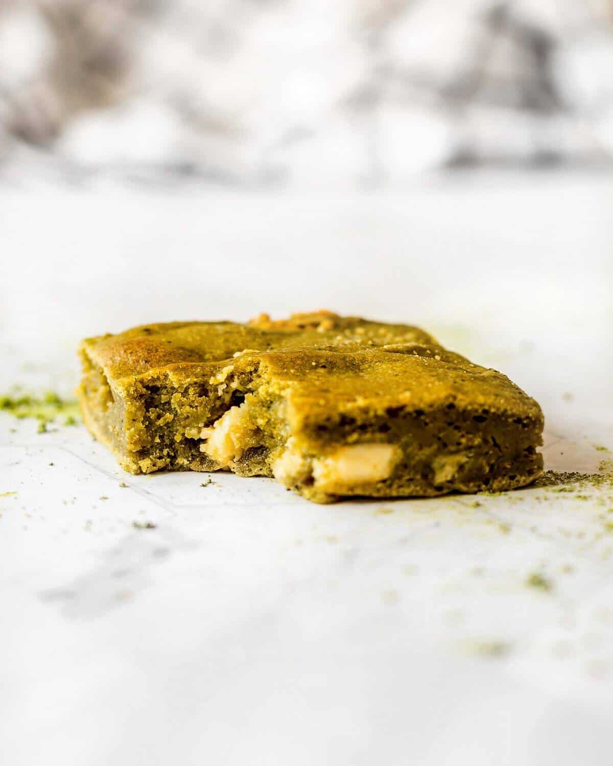 A fudgy matcha brownie with white chocolate. A bite has been taken.