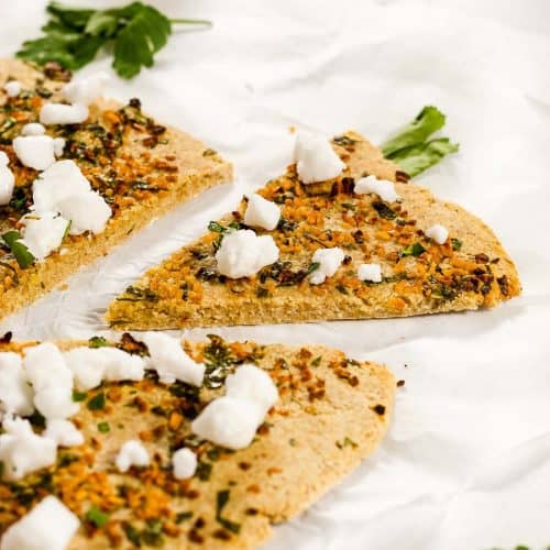 Oatmeal Pizza with garlic, parsley and feta. A slice has been cut and is pulled away from the rest of the pizza.