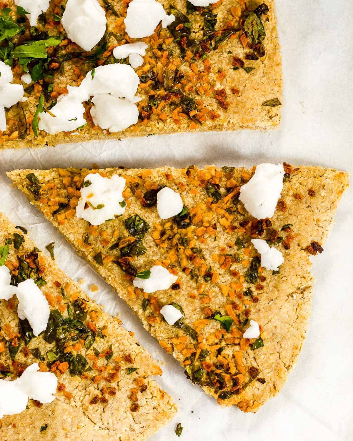 Oat Pizza Crust with garlic, parsley and feta. A slice has been cut and is pulled away from the rest of the pizza.