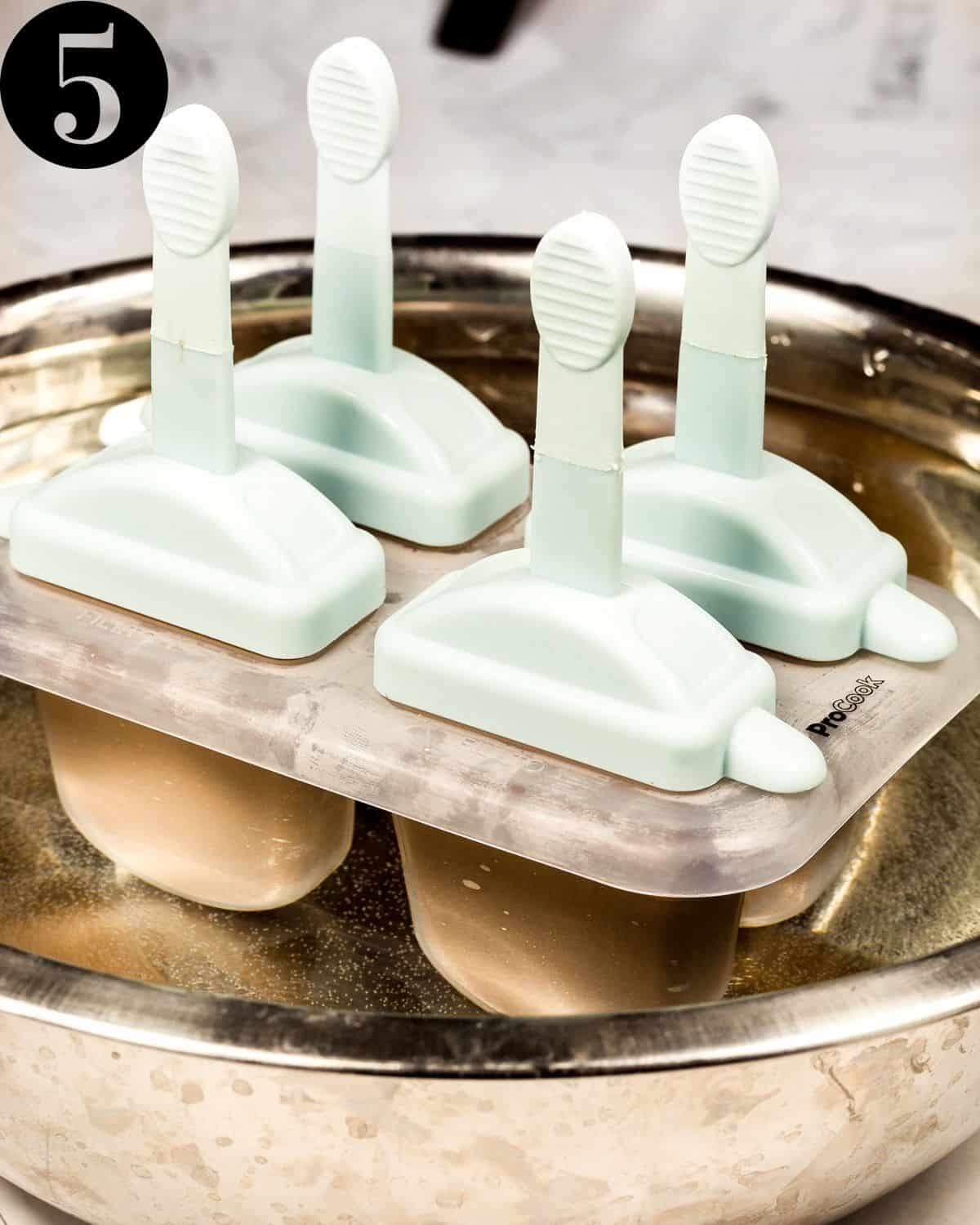 Ice cream moulds in a bowl of warm water.