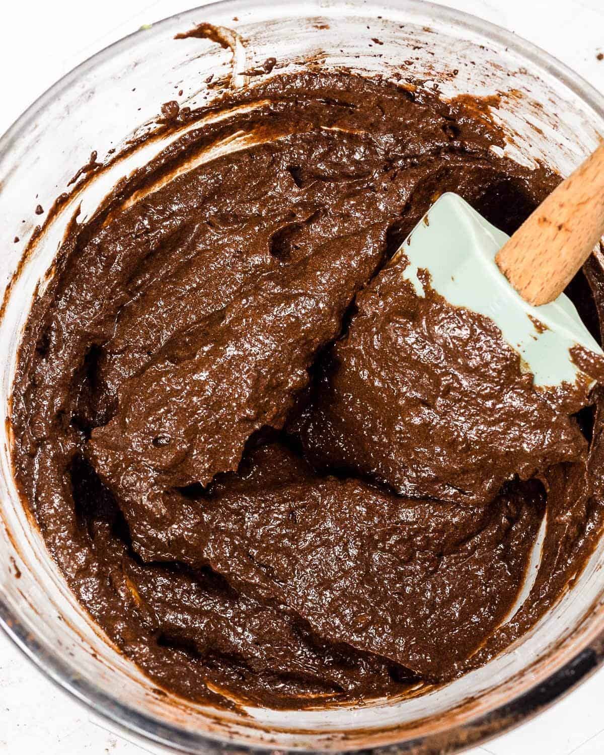 A bowl of healthy chocolate avocado frosting. There is a spatula in the bowl.