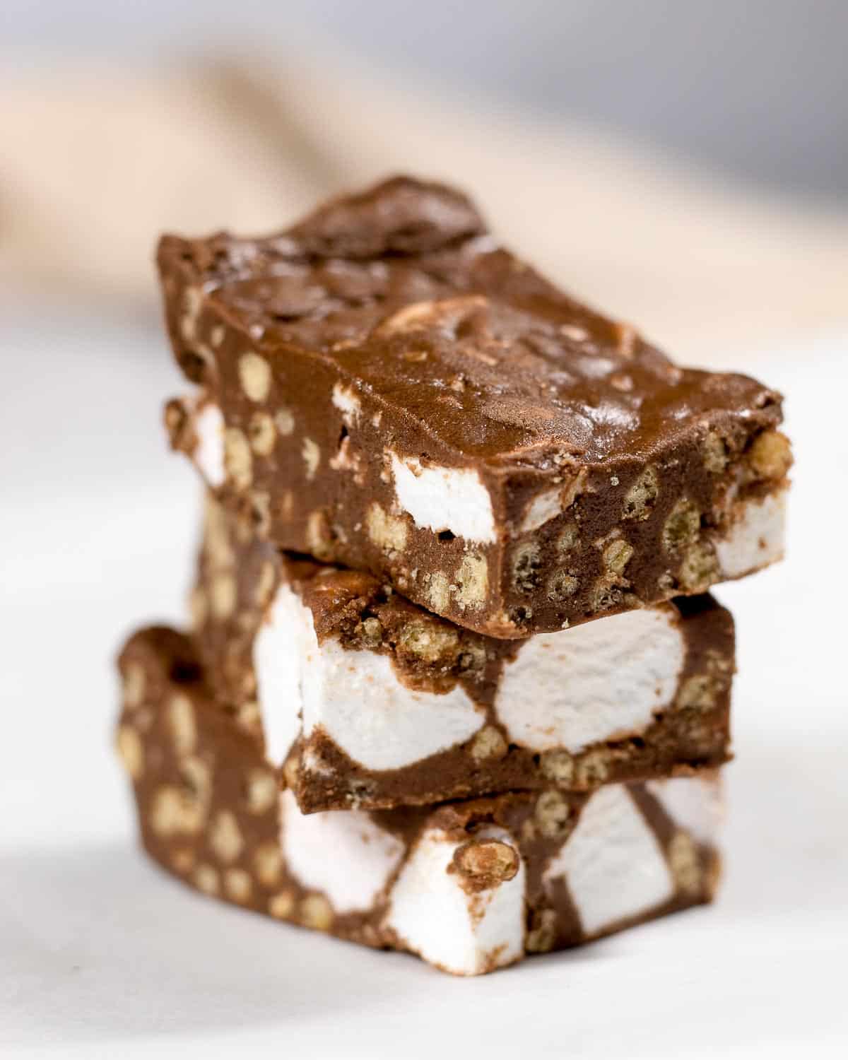 Three vegan rocky road bars with marshmallows stacked on top of each other.