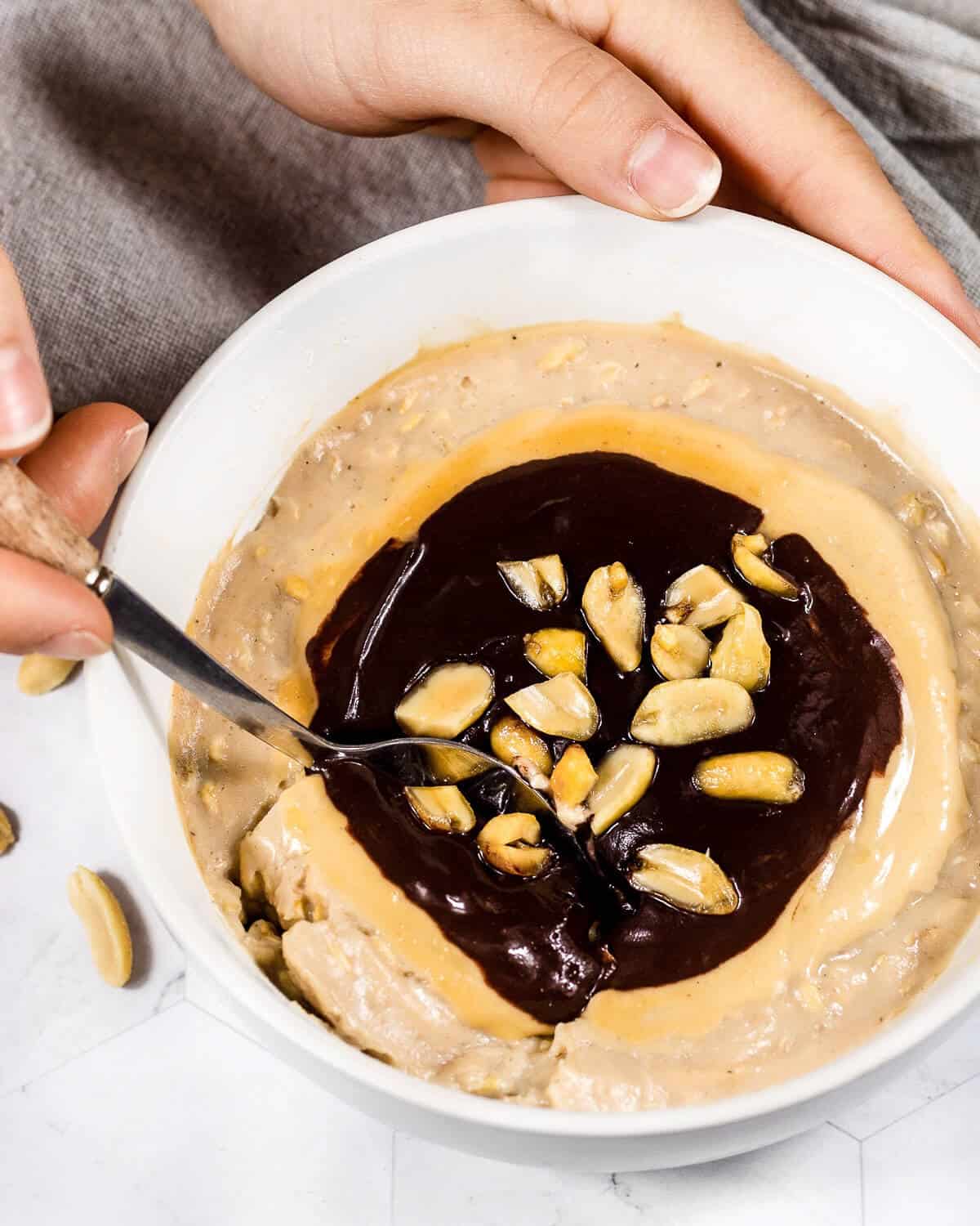 Someone is holding a bowl of snickers oats and taking a bite with a spoon.