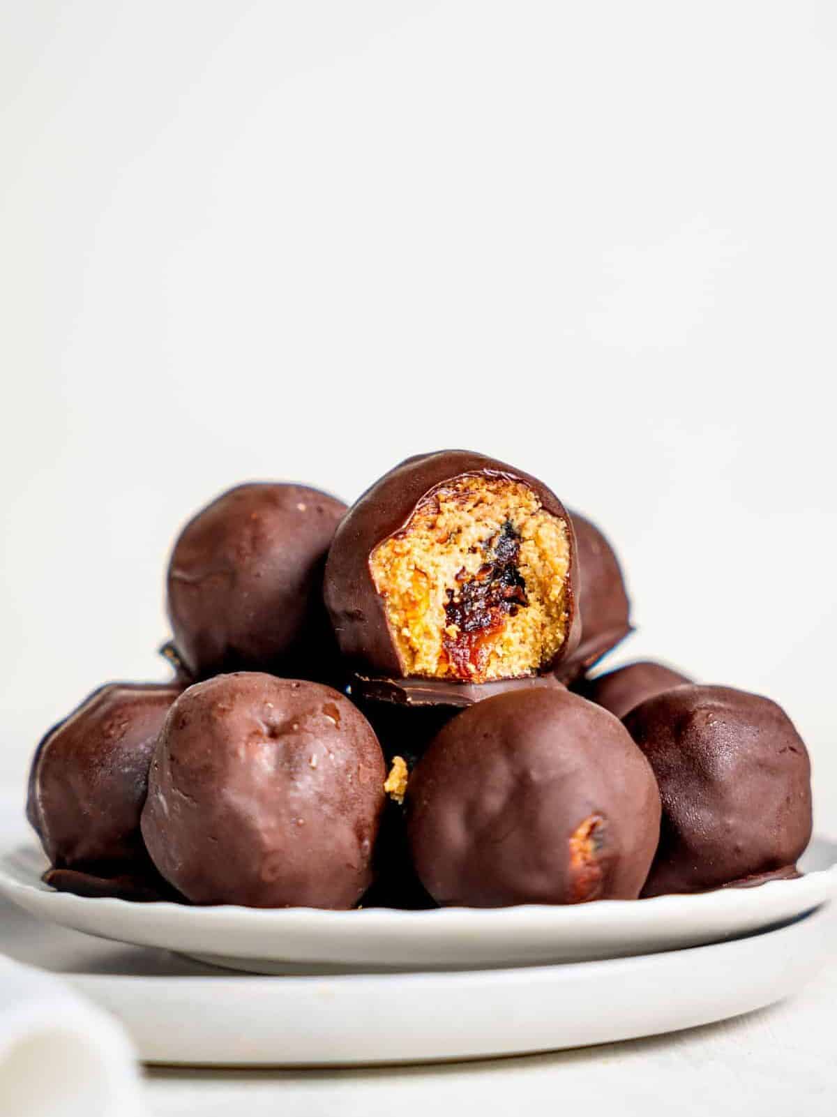 Snickers Energy Balls on a plate, one has a bite missing, revealing the inside.
