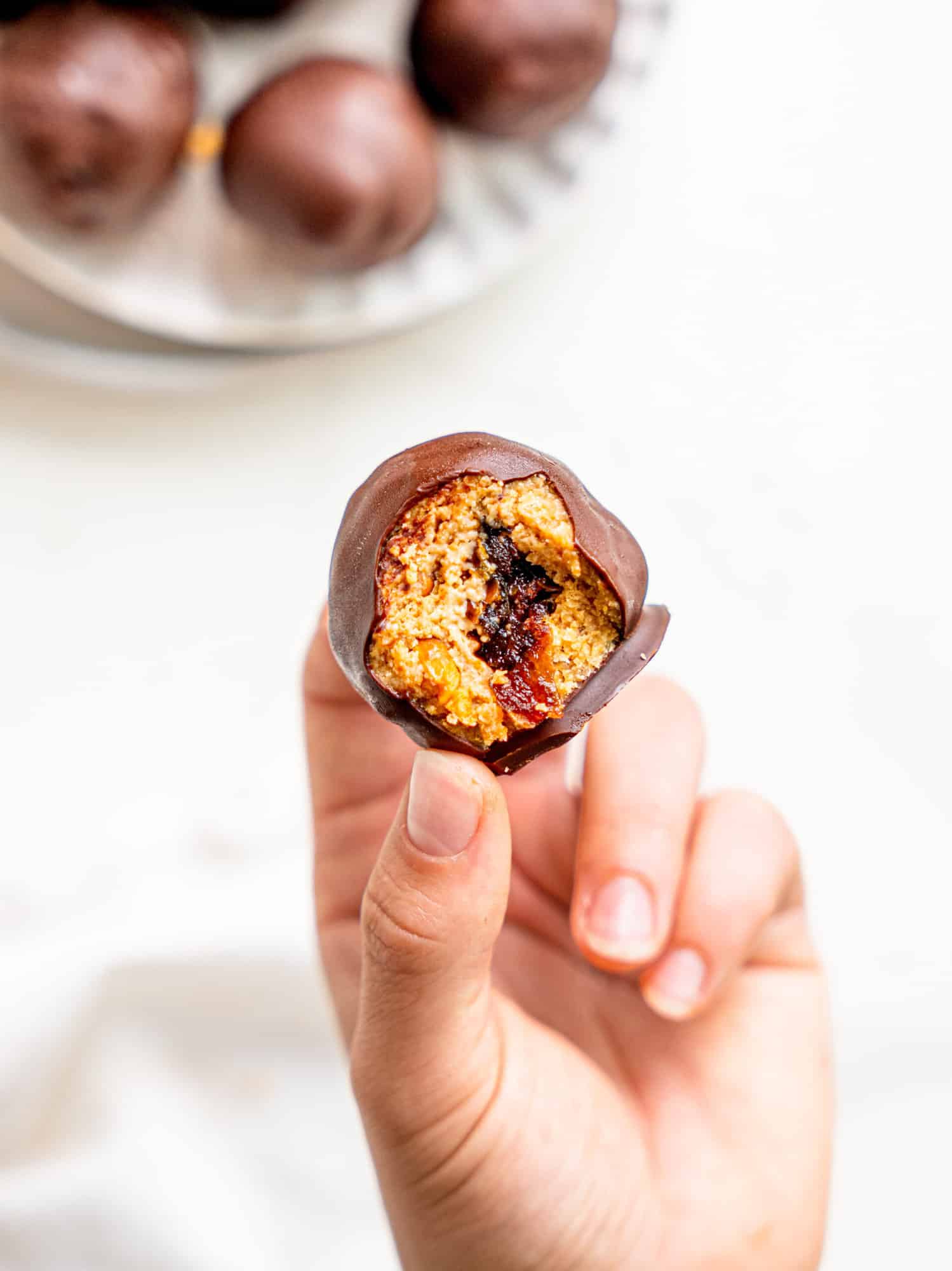 A hand holding a snickers energy balls - a bite has been taken and you can see the date in the middle.