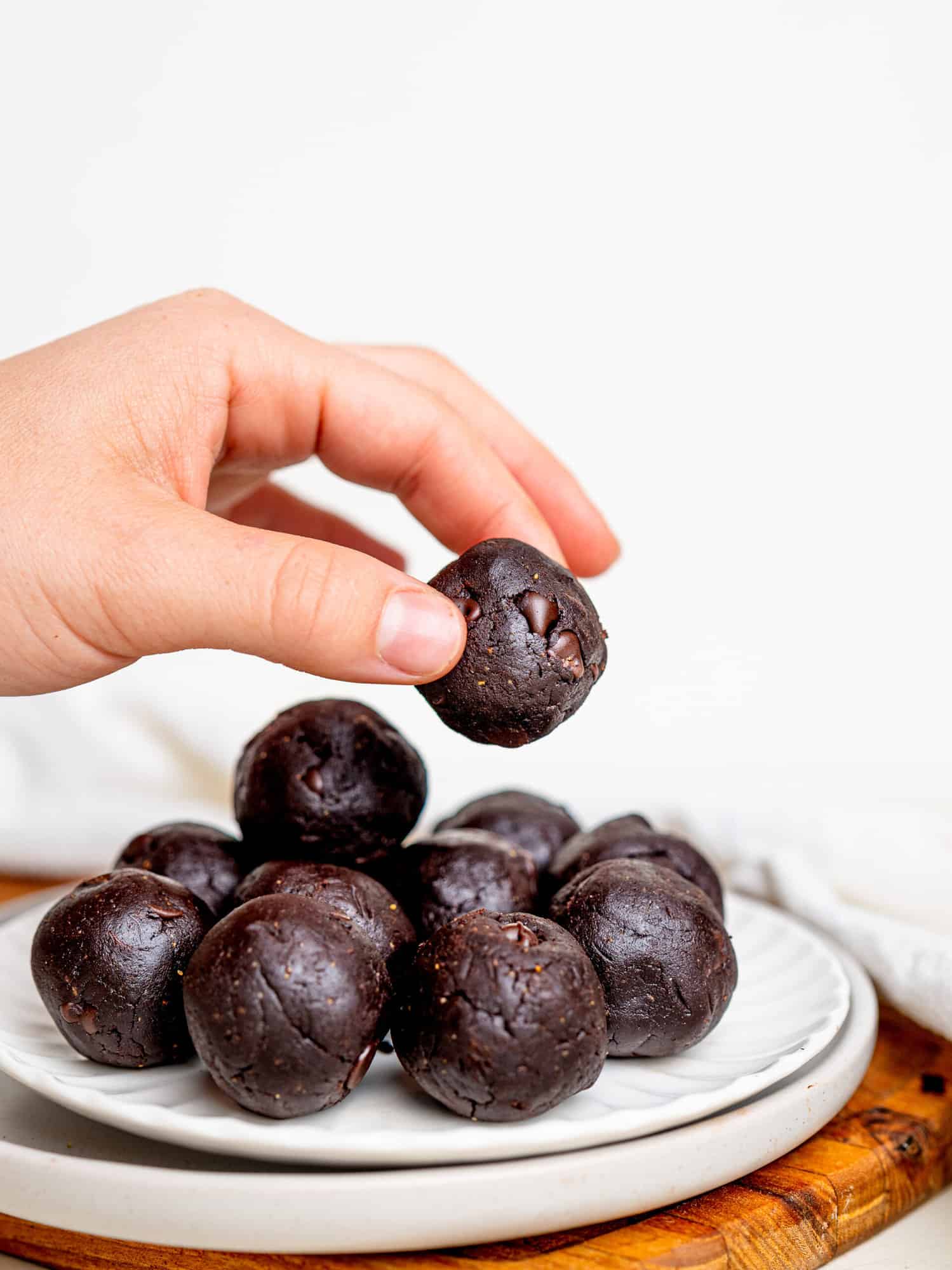 Easy and Healthy Brownie Batter Bites on a plate. Someone is holding one.