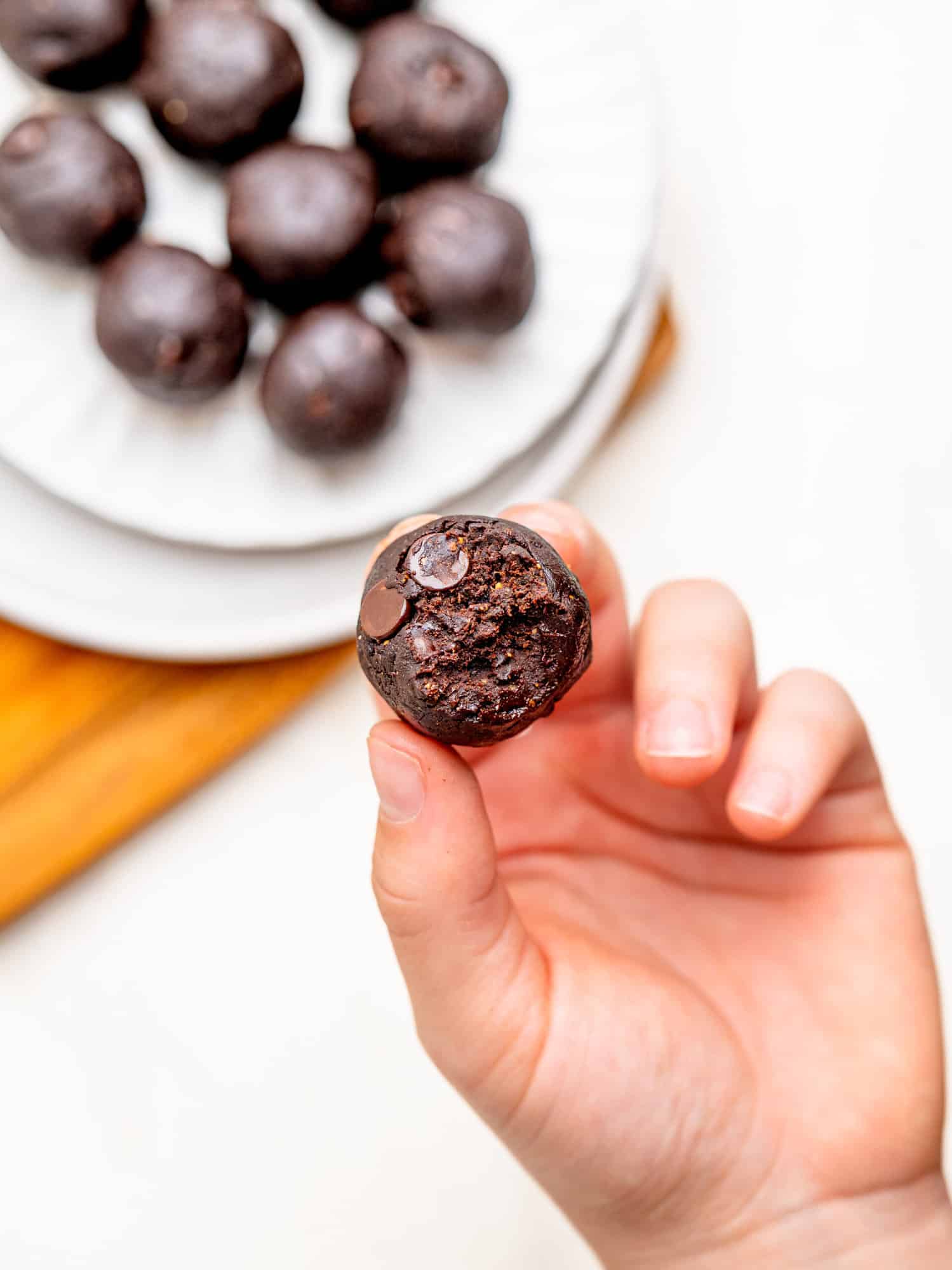 Someone holding a bitten brownie batter bite.