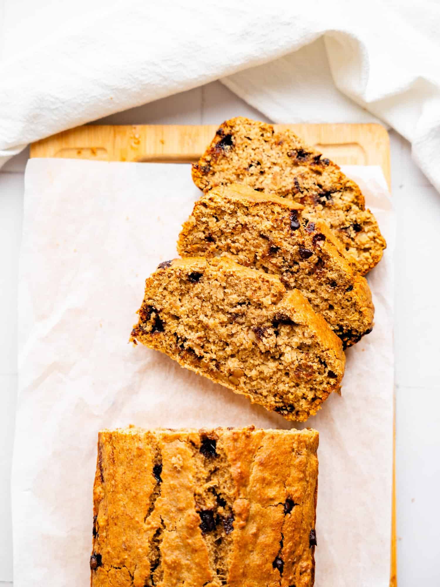 Oat Flour Banana Bread, half-sliced on a cutting board.