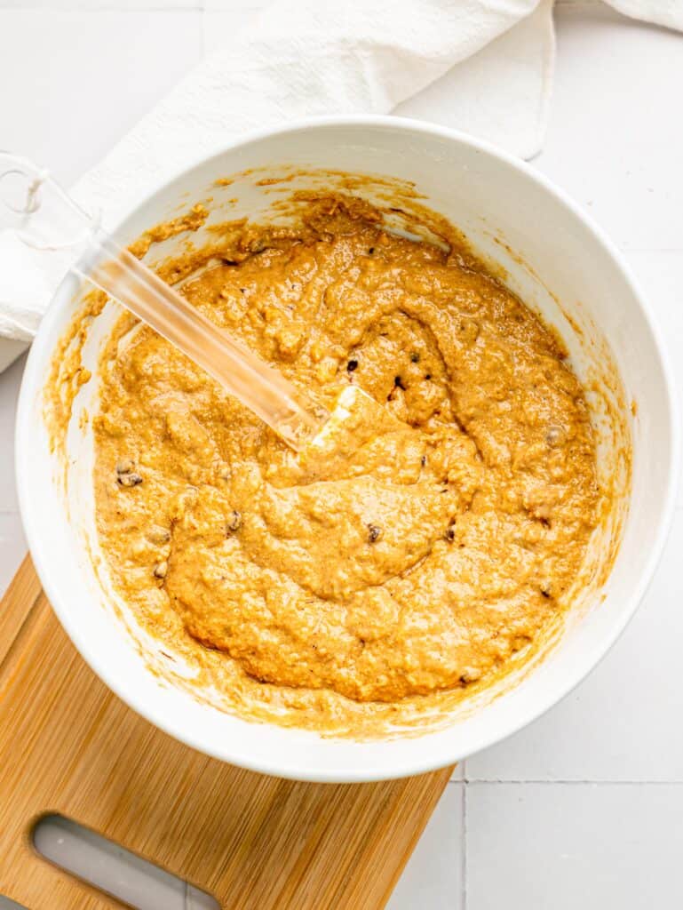 Oat Flour Banana Bread batter with chocolate chips and walnuts in a ixing bowl.