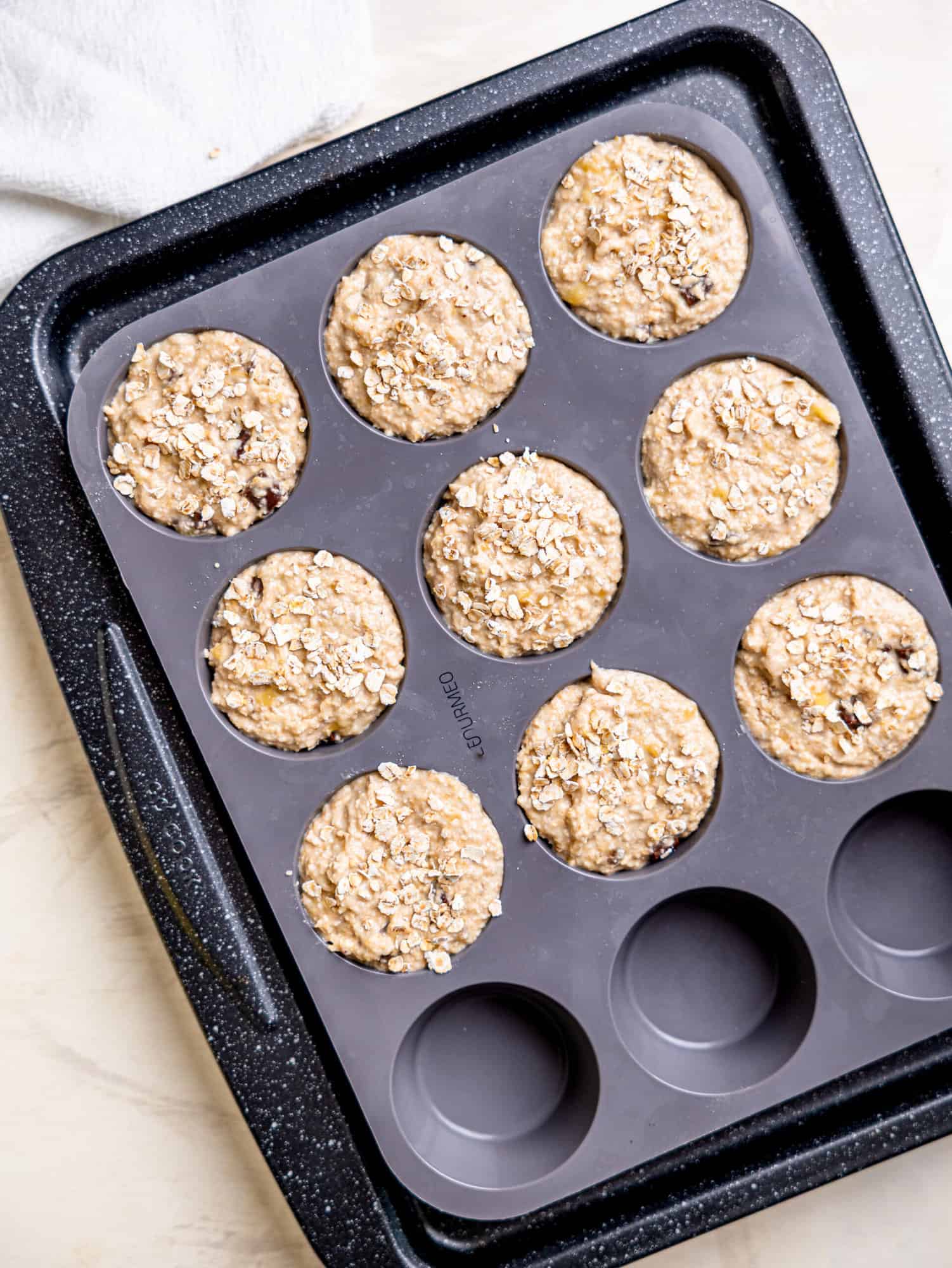 Banana oatmeal muffin batter portioned into a silicone muffin tray before baking.