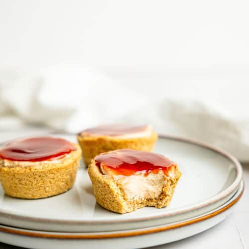 Three mini protein cheesecakes on a plate, one is half-eaten.