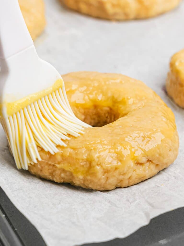 Brushing egg wash on a blueberry bagel.