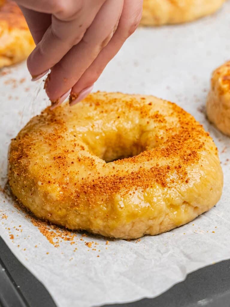 Sprinkling coconut sugar on a blueberry bagel before baking.