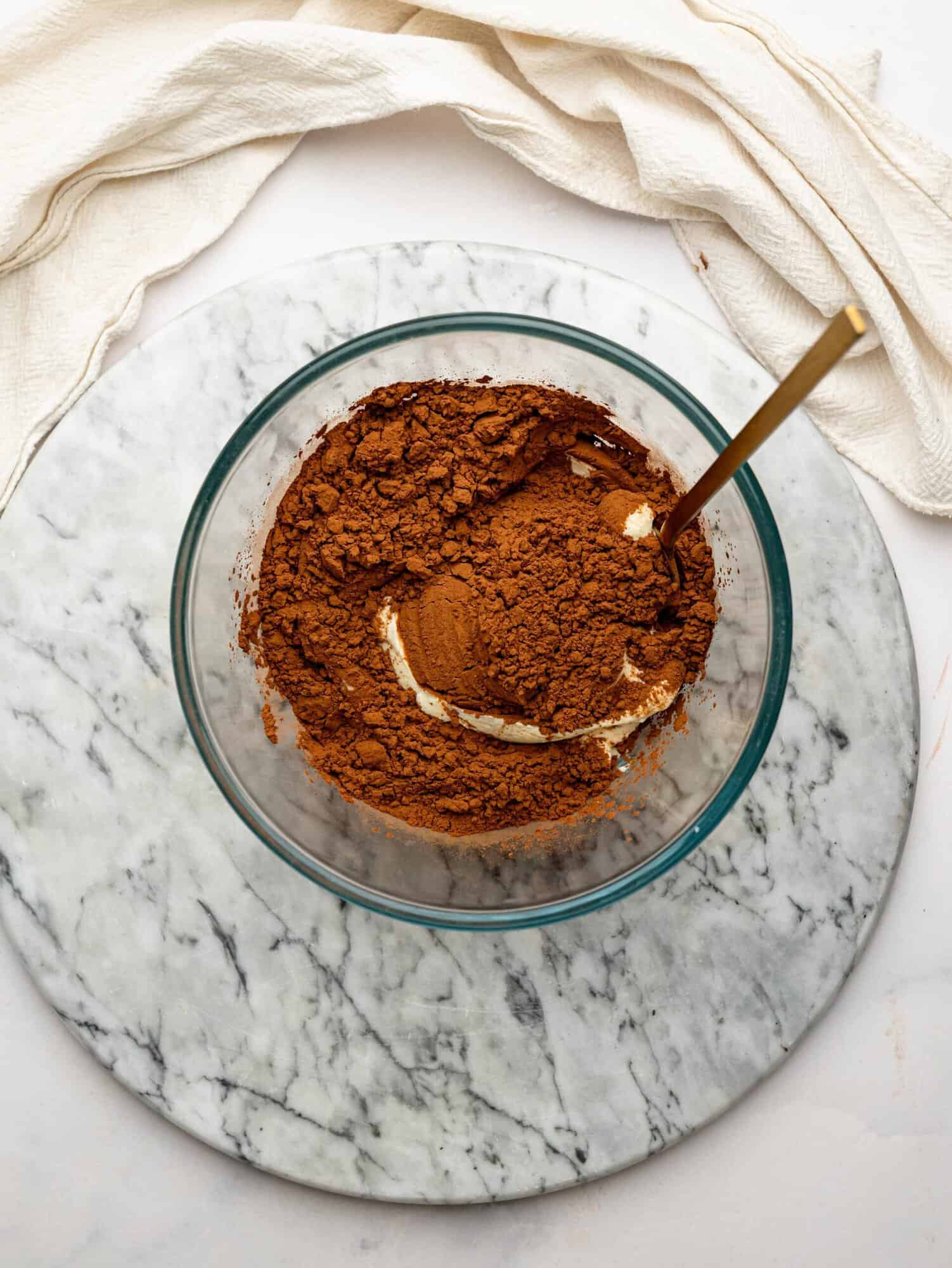 Unsweetened cocoa powder being mixed into whipped cottage cheese.