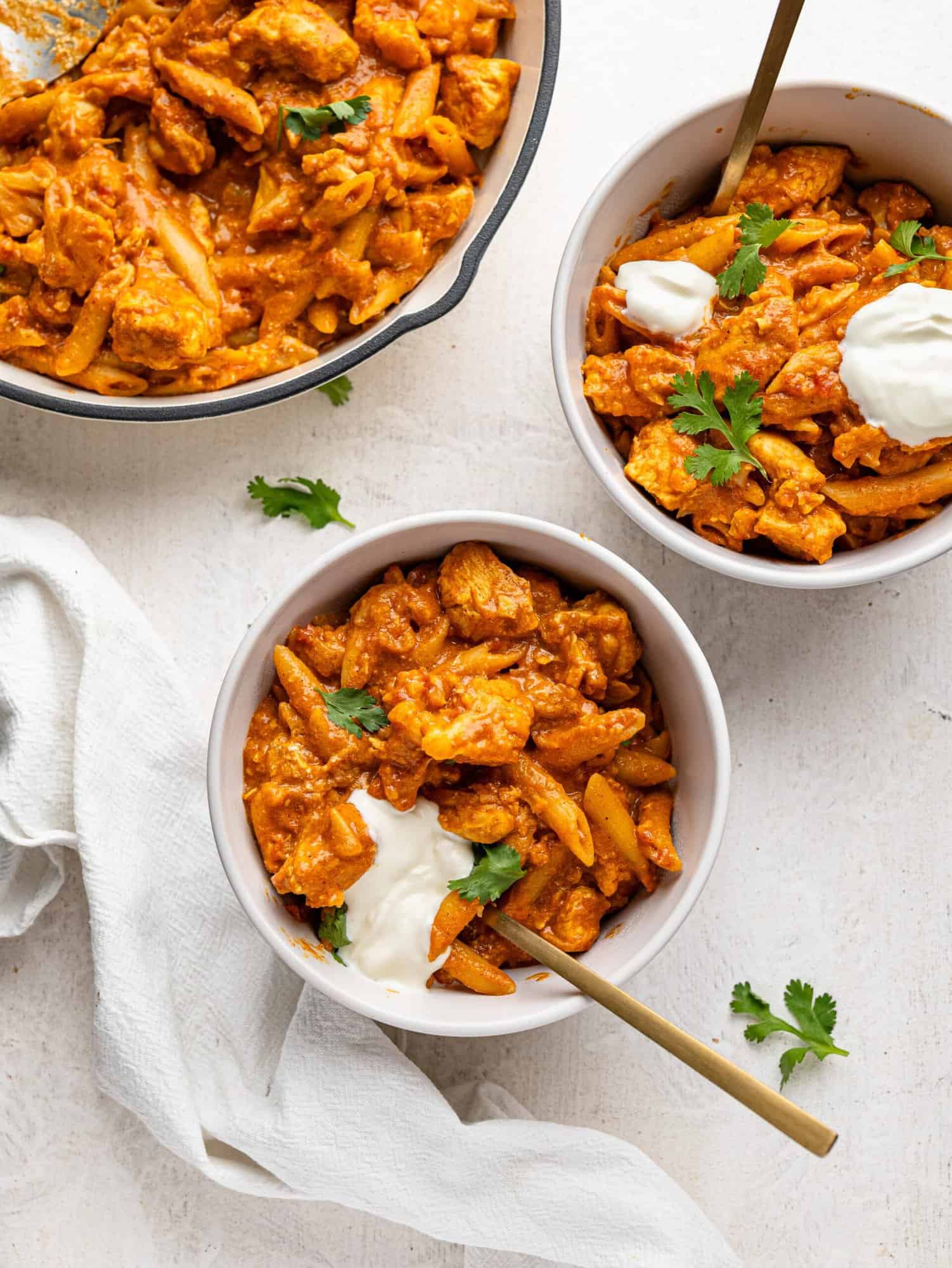 Bird's eye view of two bowls of butter chicken pasta.
