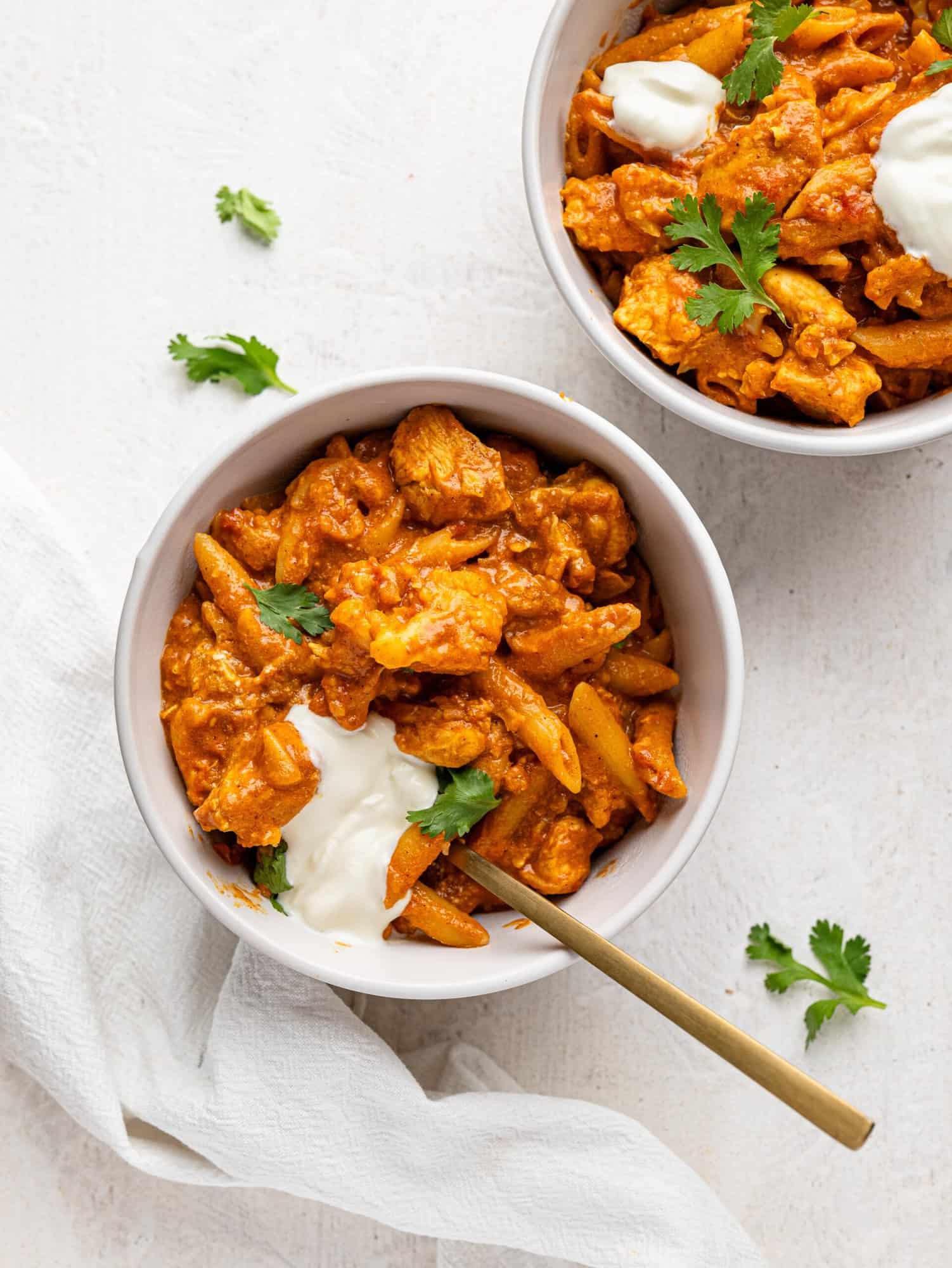 Bird's eye view of two bowls of butter chicken pasta.