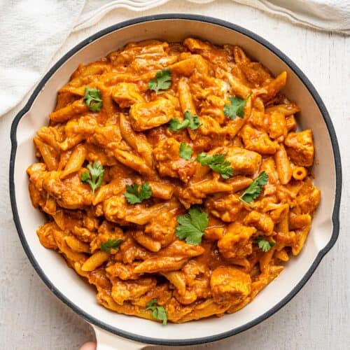 Bird's eye view of butter chicken pasta in a white pan.