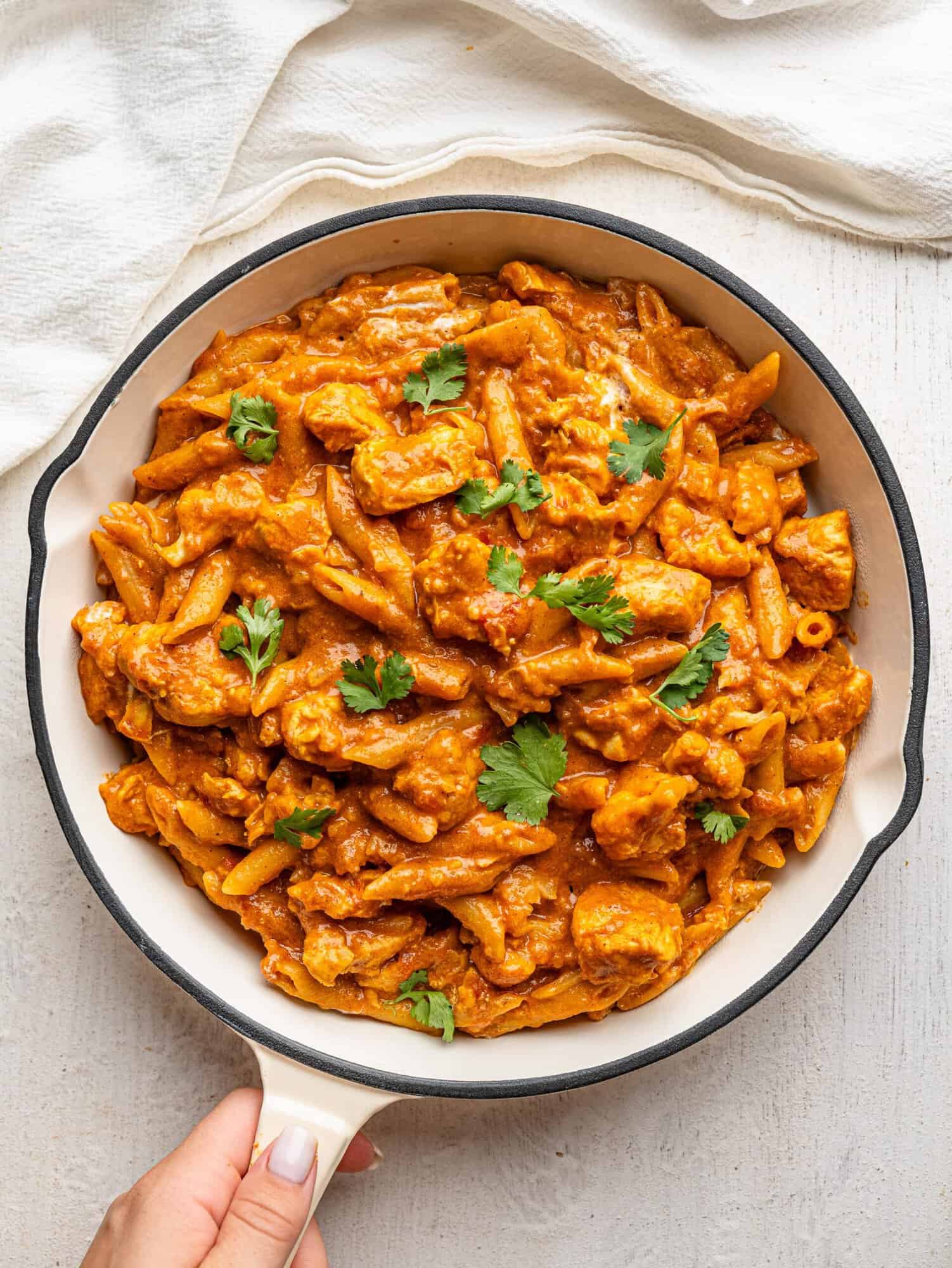 Bird's eye view of butter chicken pasta in a white pan.