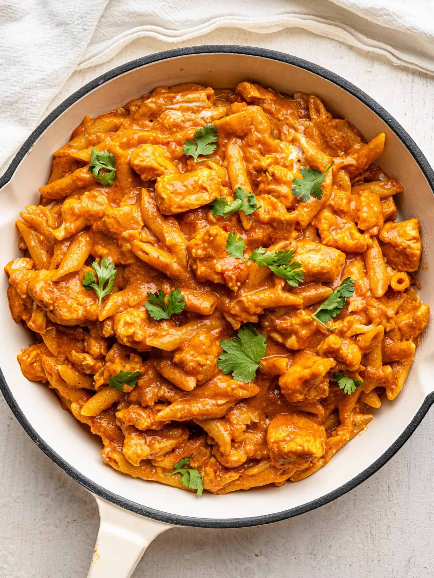 Bird's eye view of butter chicken pasta in a white pan.