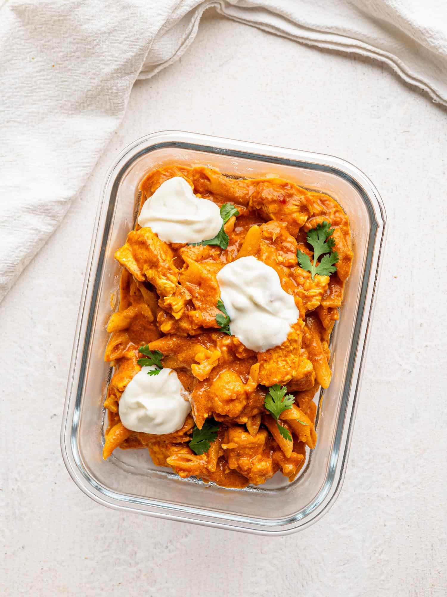 Butter chicken pasta in a glass meal prep container.