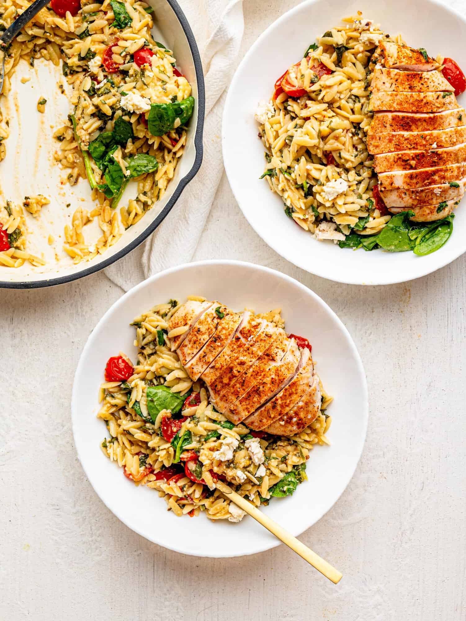 Bird's eye view of two white bowls with chicken and orzo bake.