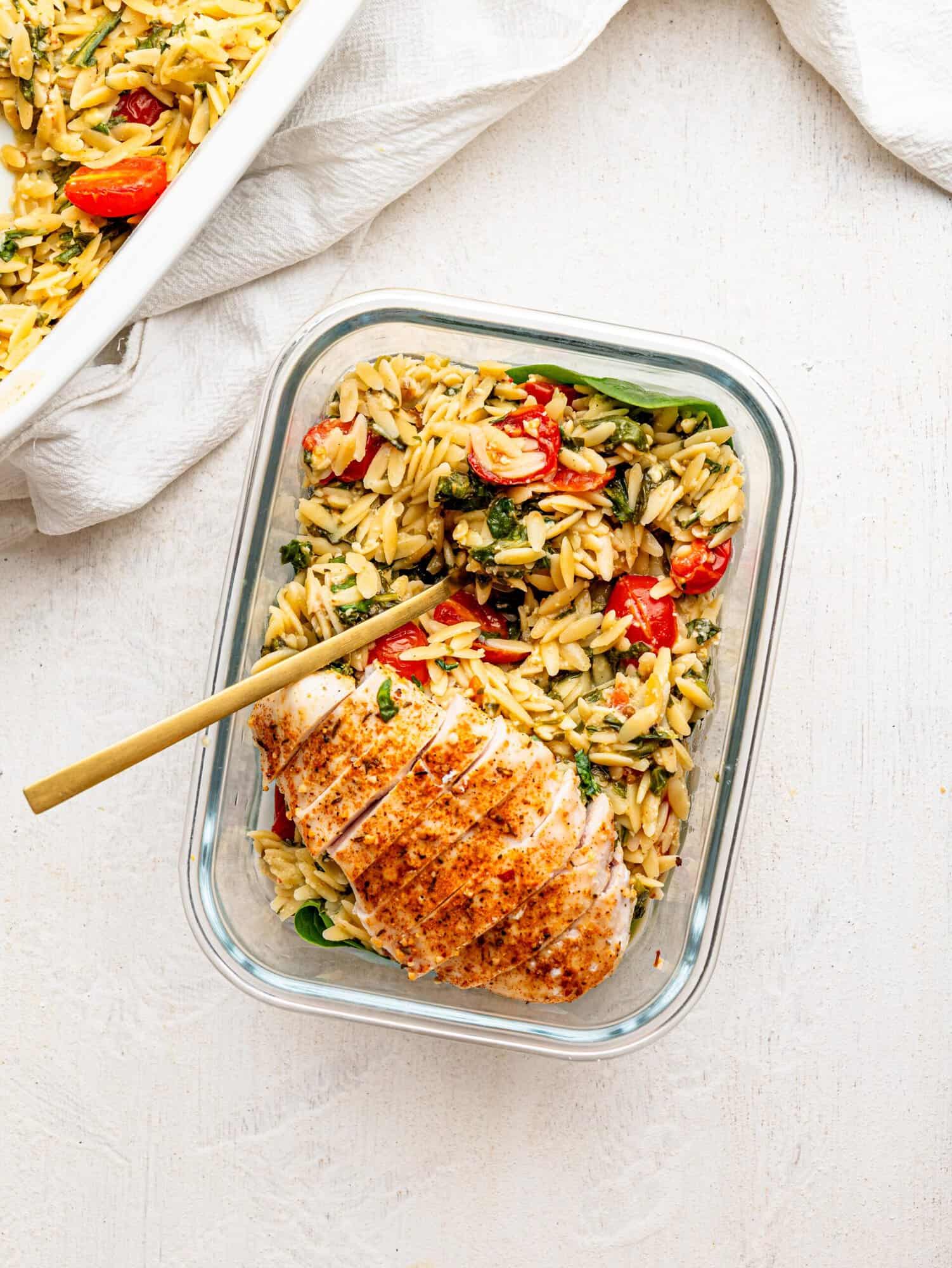 Chicken and Orzo Bake in a glass meal-prep container.