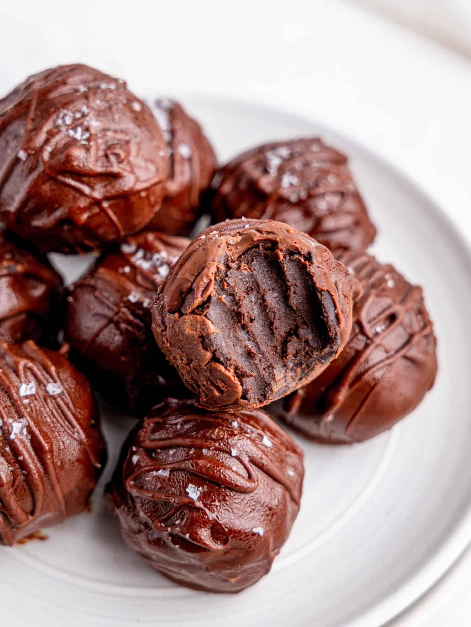 Chickpea chocolate truffles stacked on top of each other on a white plate.