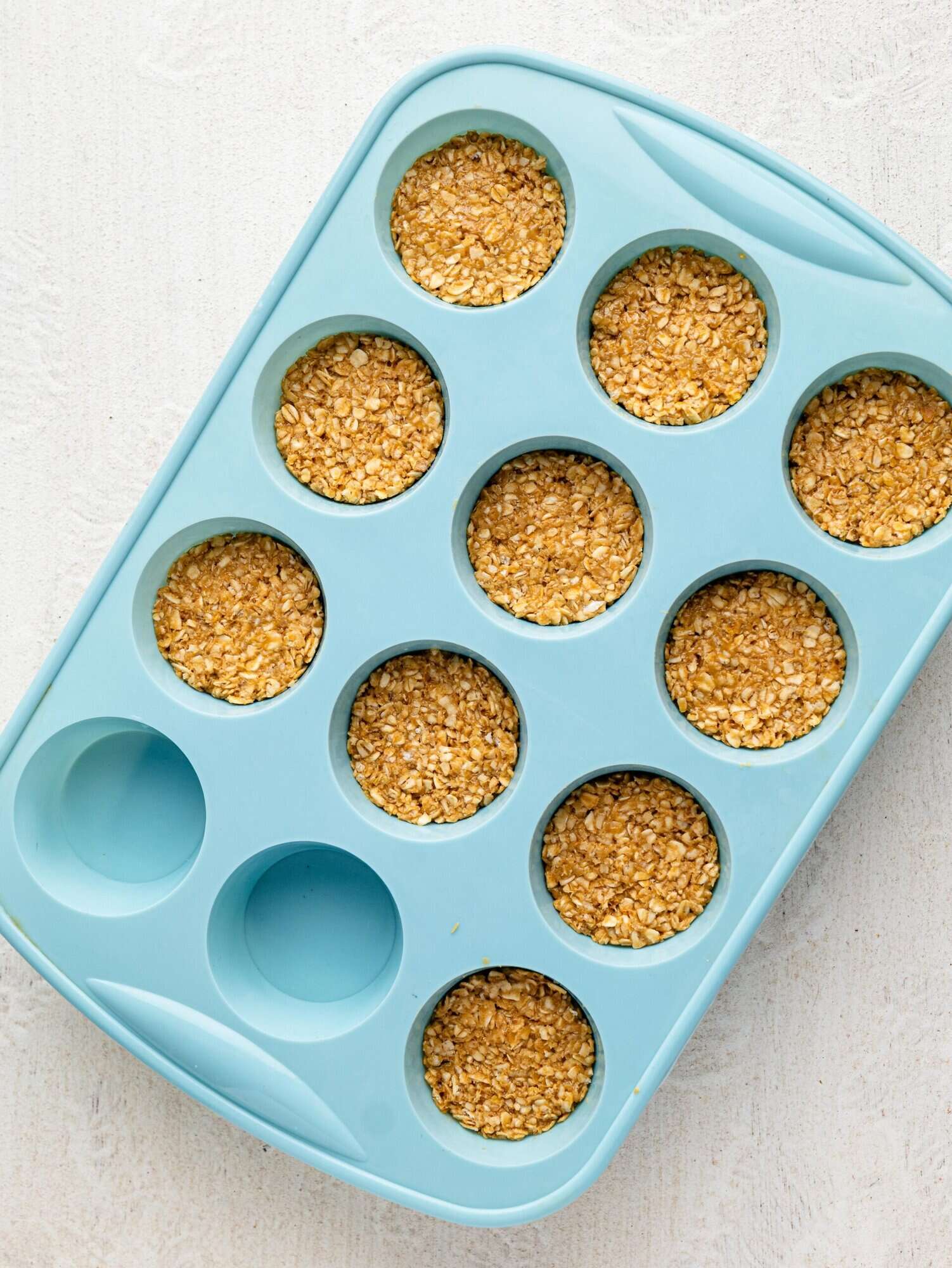 Peanut butter, honey, and oats pressed into a silicone muffin tray.