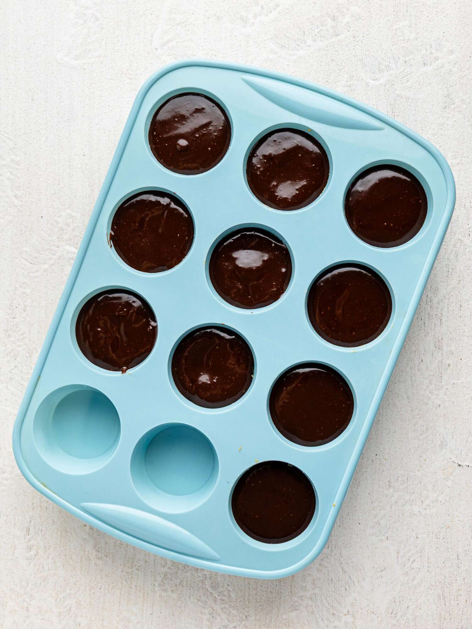 Peanut butter, honey, and oats pressed into a silicone muffin tray, topped with chocolate ganache.