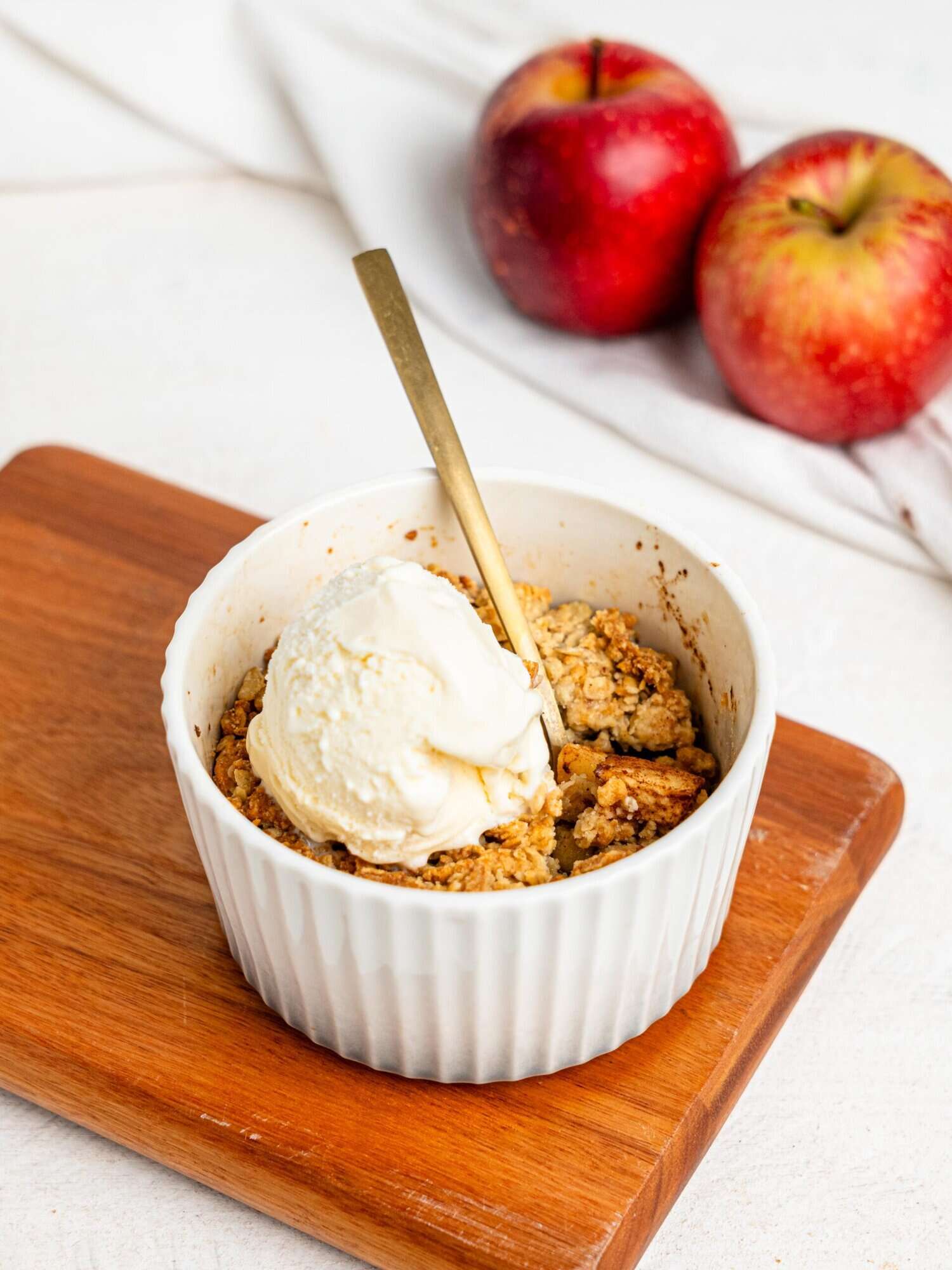 Single Serve Apple Crumble in a small ramekin topped with vanilla ice cream.