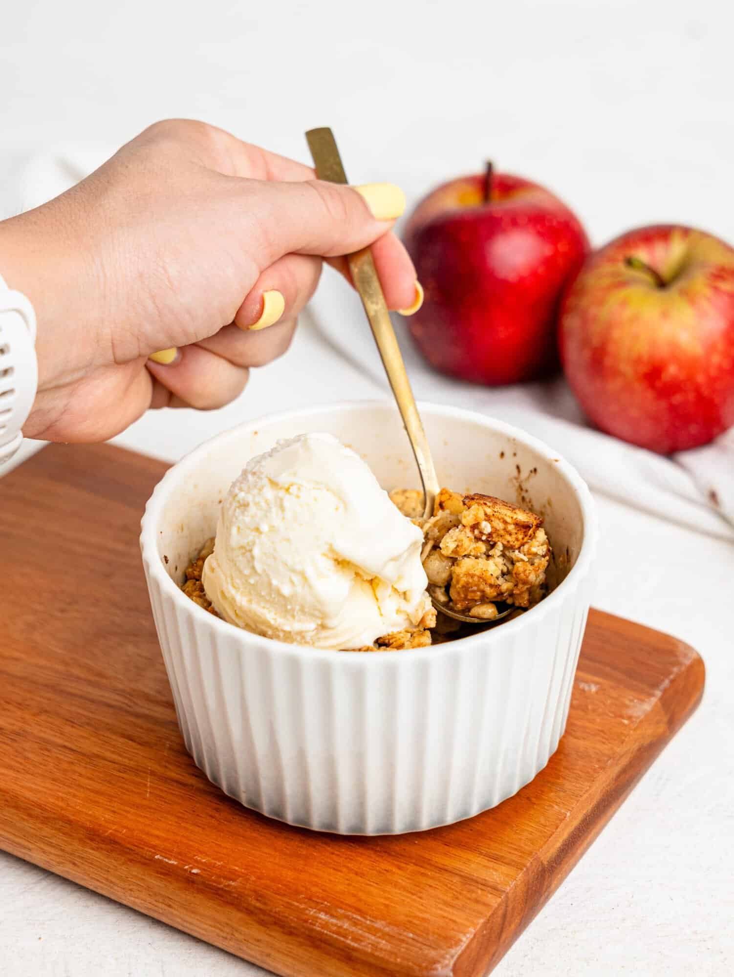 Single Serve Apple Crumble in a small ramekin topped with vanilla ice cream.