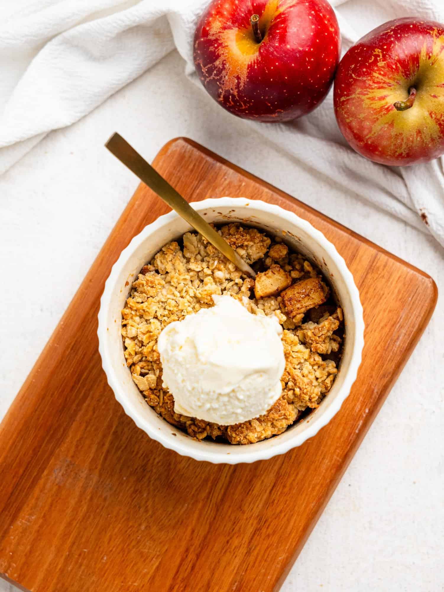 Single Serve Apple Crumble in a small ramekin topped with vanilla ice cream.