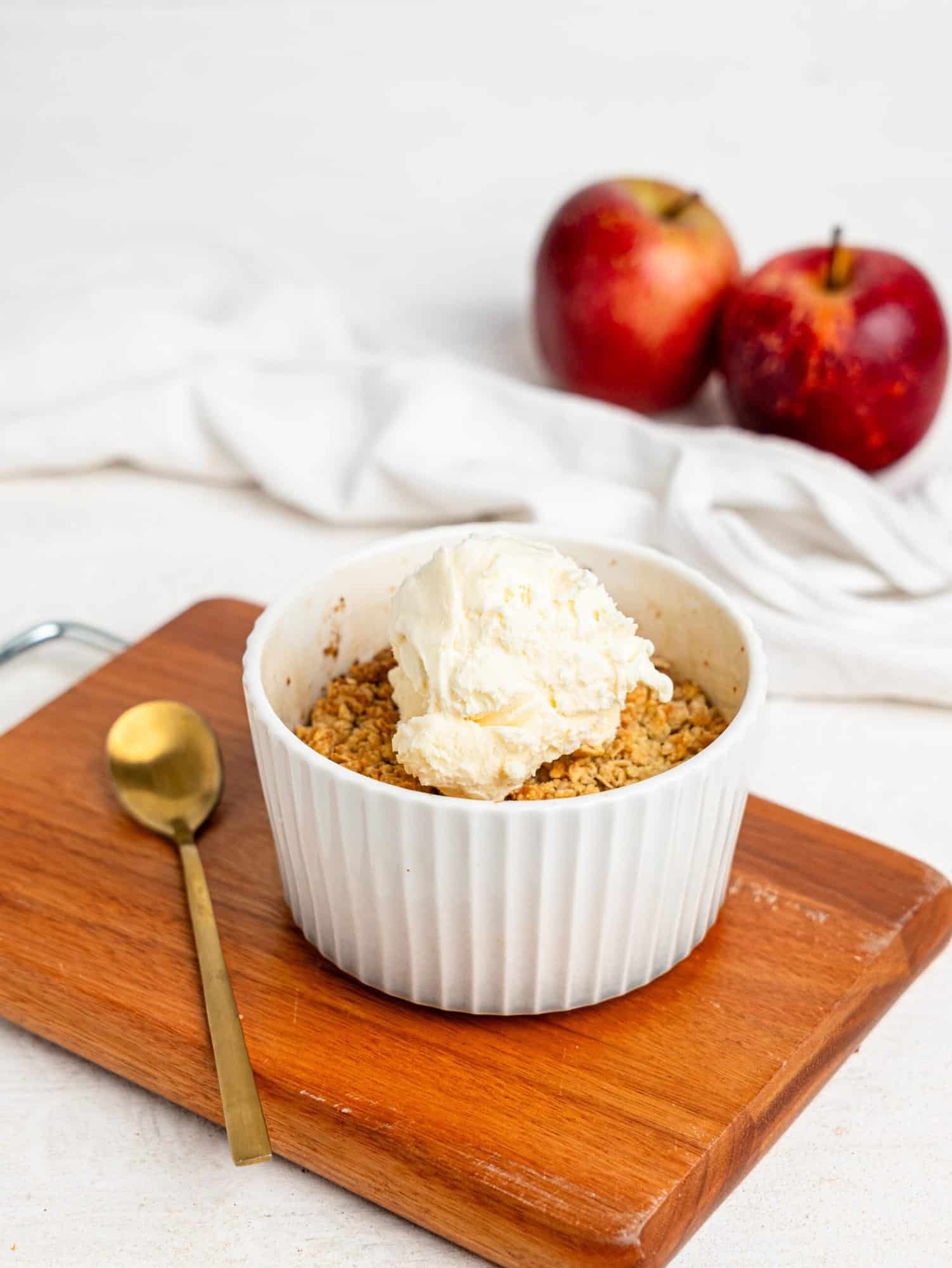 Single Serve Apple Crumble in a small ramekin topped with vanilla ice cream.