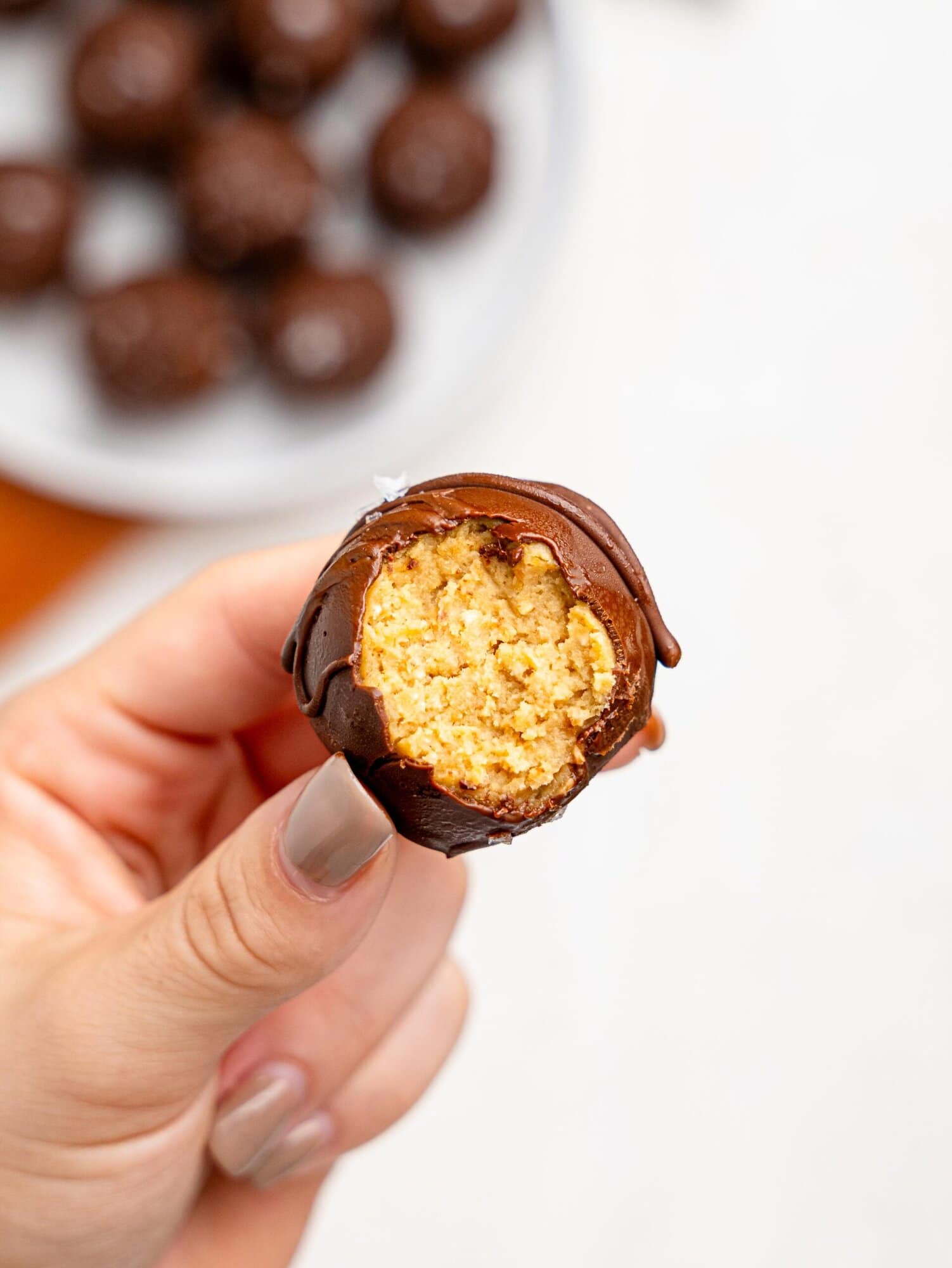A hand holding a half-eaten Chickpea cookie dough truffle.