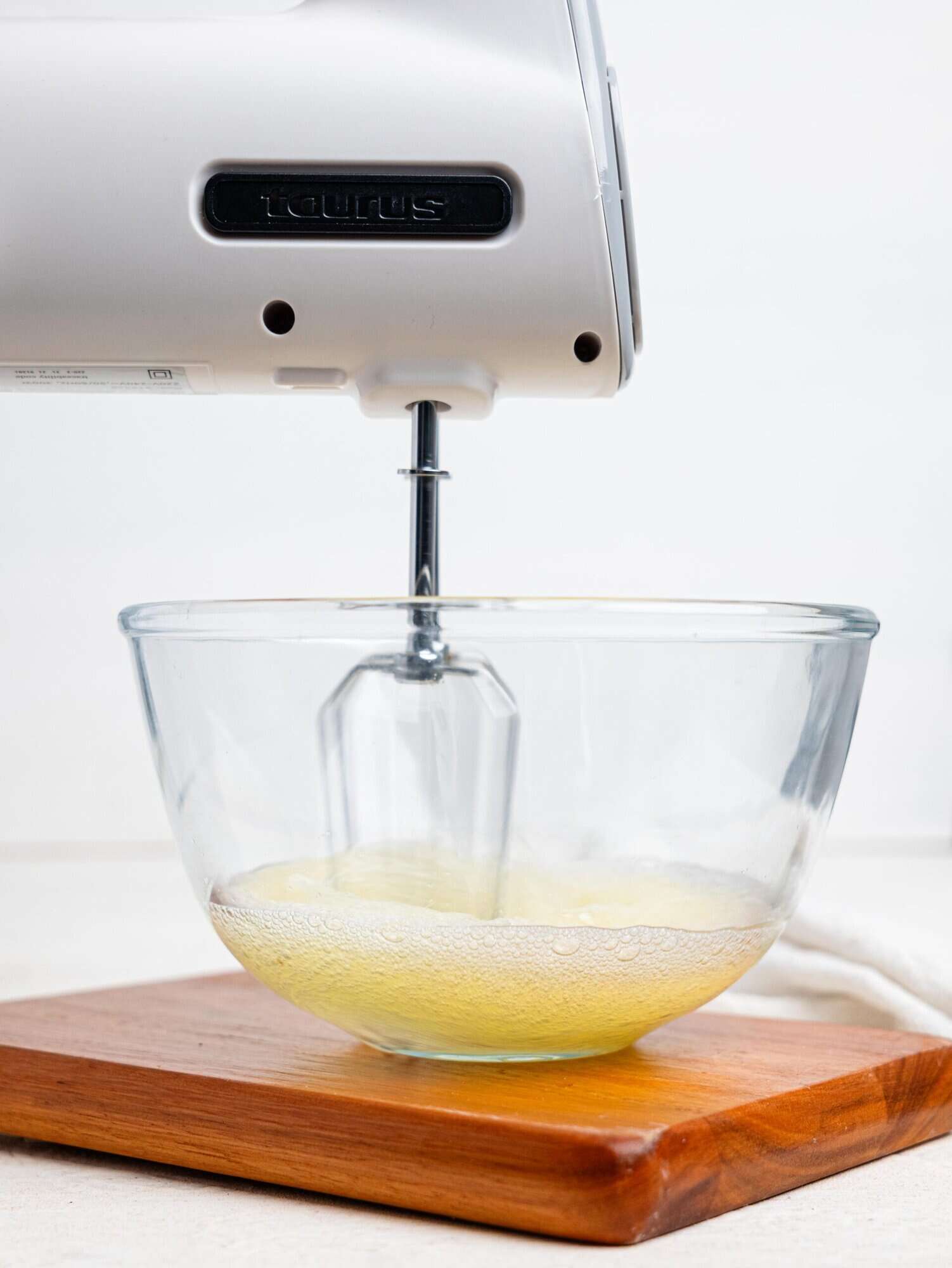 Egg whites being whipped in a glass bowl.