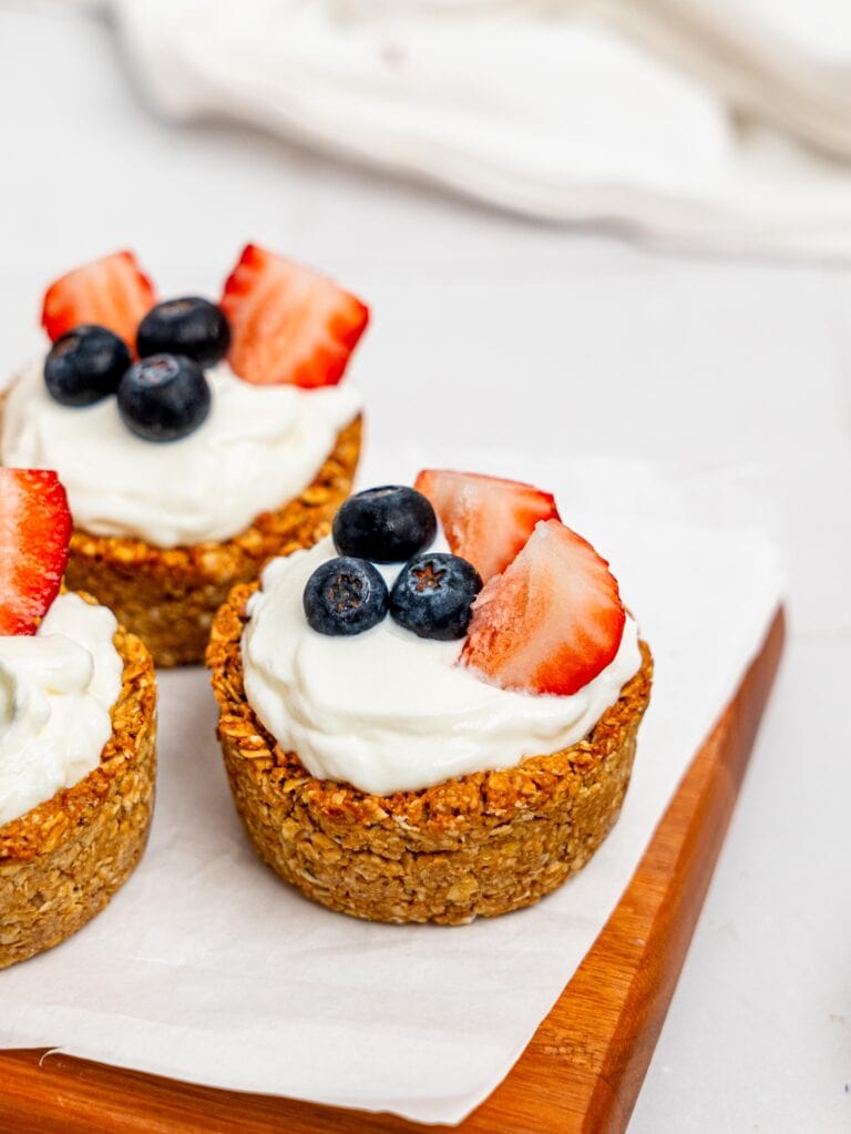 Granola Cups filled with yoghurt and berries on a wooden board.