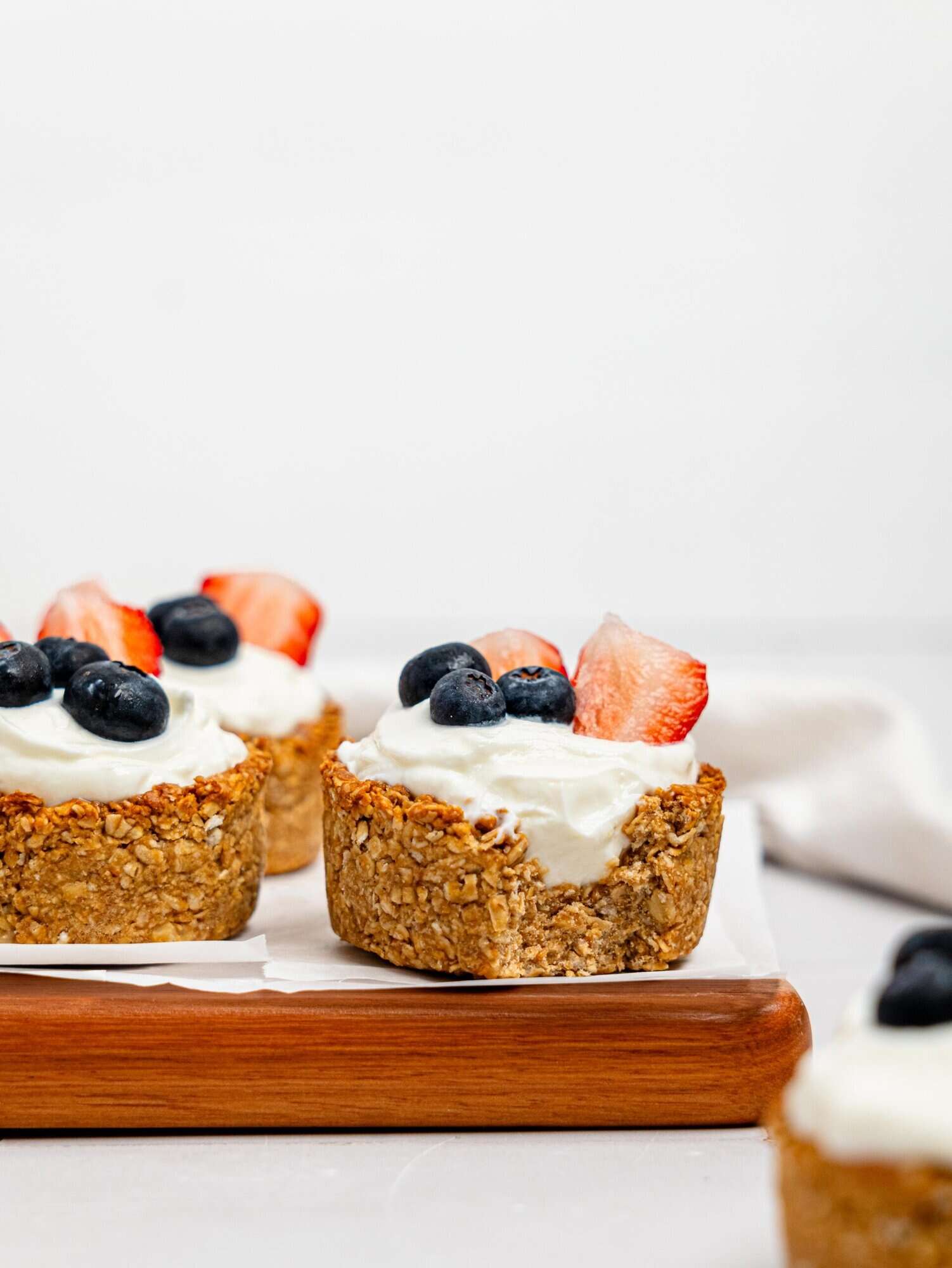 Granola Cups filled with yoghurt and berries on a wooden board.