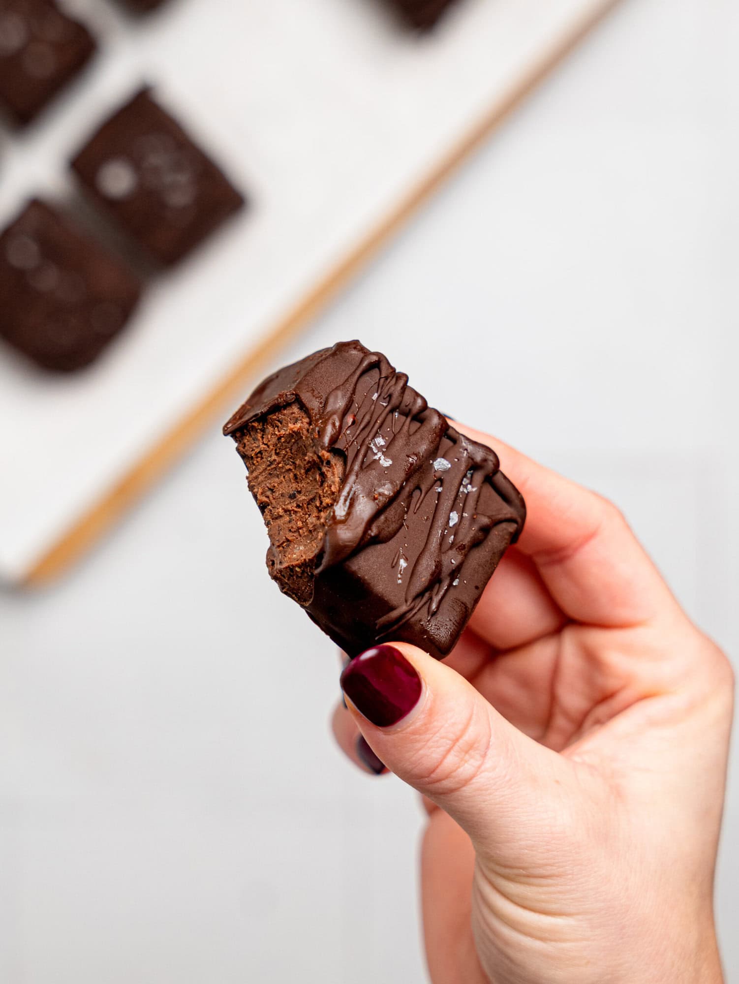 A hand holding a half-eaten black bean brownie.