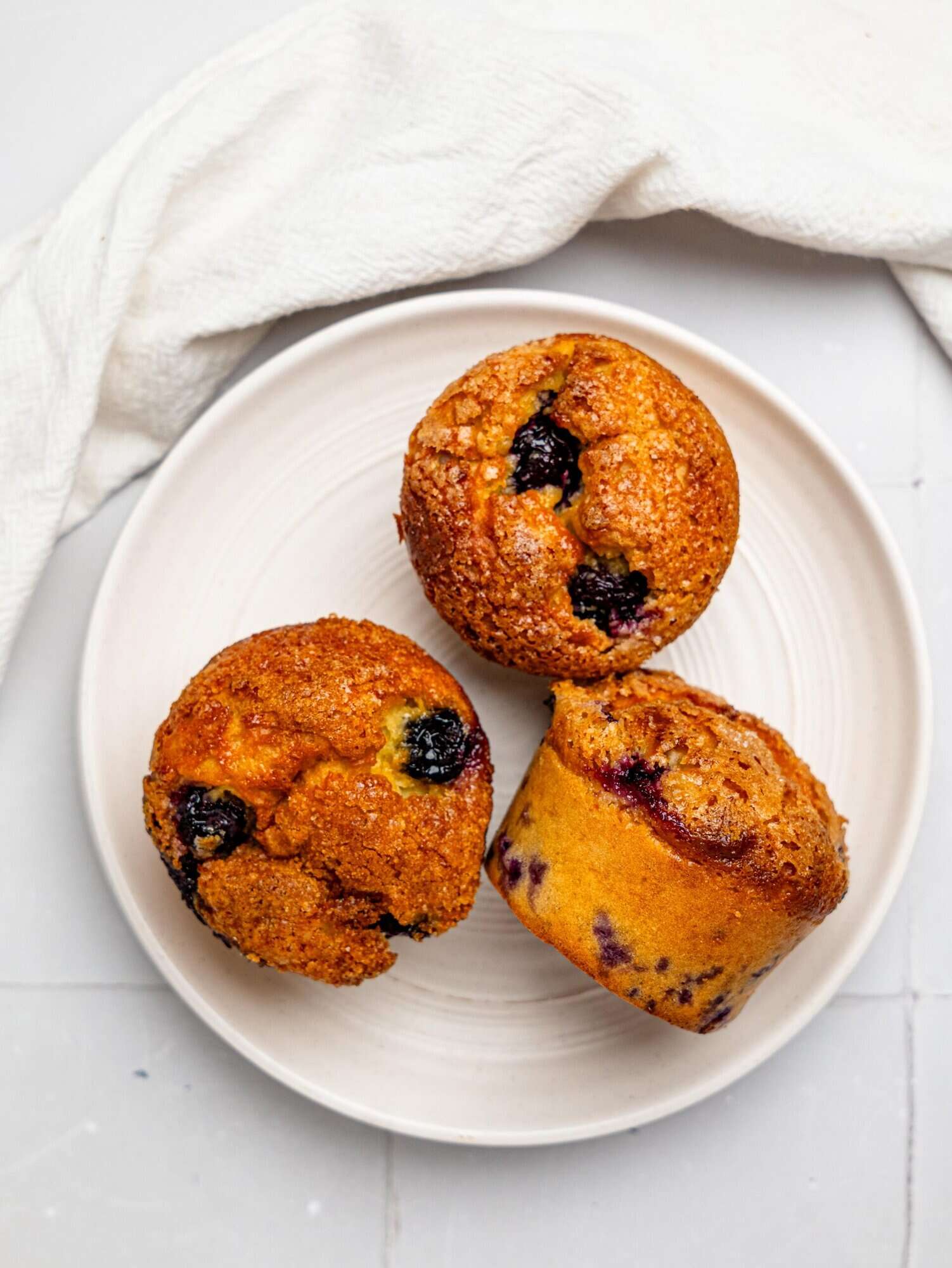 Three cottage cheese blueberry muffins on a white plate.