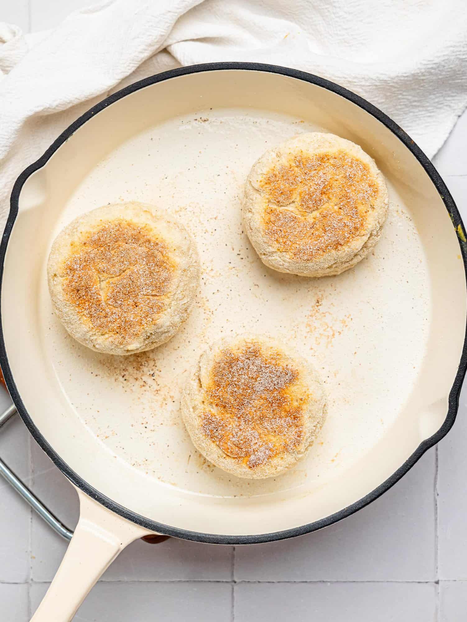 Cooking english muffins in a cast iron pan.