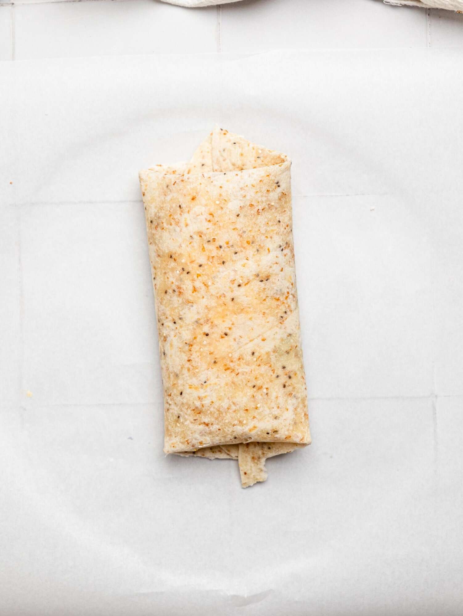 A tuna melt wrap on parchment paper.