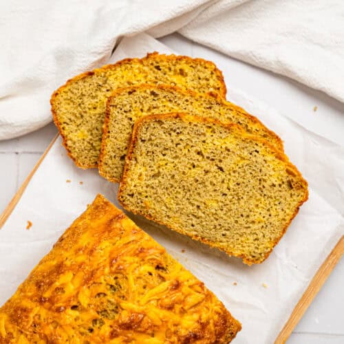 Sliced cheesy oat flour bread on a cutting board.