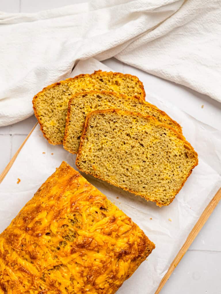 Sliced cheesy oat flour bread on a cutting board.